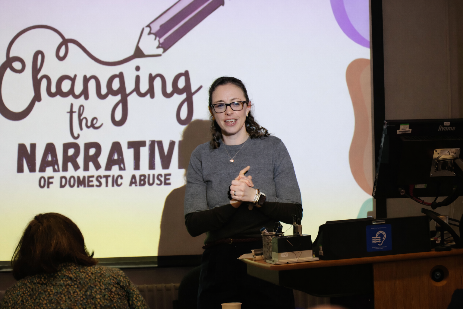 Rebecca Shaw presenting in front of a screen which says 'Changing the narrative of domestic abuse'.